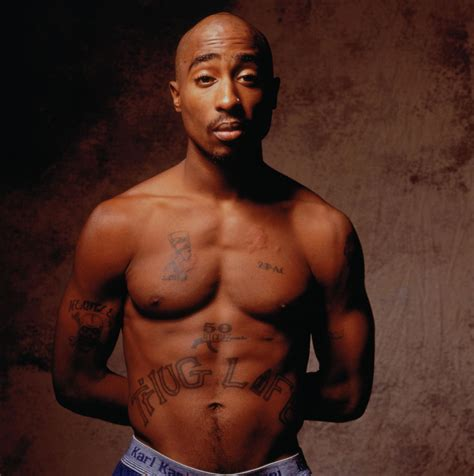 Tupac Shakur shirtless exposing his tattoo that says thug life