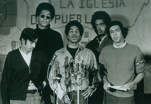 black and white photo of young latinos talking in front of a microphone to protest conditions for Latinos in Chicago 