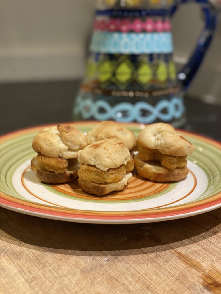 mini chicken sandwiches on a southwestern orange plate with a pitcher painted with Mexican designs in turqoise and blue