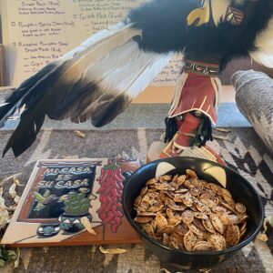 roasted pumpkin seeds with tile that says "mi casa es su casa" and a kachina doll with wings outstretched looking up to the sky